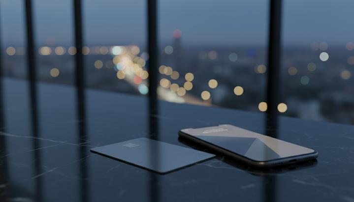 JPMorgan выкупает у Goldman Sachs портфель кредитных карт Apple Металлическая кредитная карта лежит на темном мраморном столе рядом со смартфоном в современном офисном пространстве.