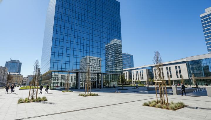 Современное стеклянное офисное здание банка на фоне голубого неба, расположенное в деловом квартале европейского города.